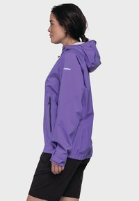 Lila wasserdichte Jacke mit Kapuze, elastischen Bündchen, einer Reißverschlusstasche und einem Kordelzug am Bund. Leichtes Material mit glatter Textur.