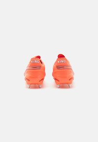 Scarpe da calcio rosso-arancioni con tomaia testurizzata, prominente branding "KING" sul tallone e tacchetti argentati per la trazione.