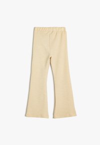 Beige flared bukser lavet af tekstureret stof med elastisk talje. Bukserne er glatte og har en tapered pasform mod knæet.