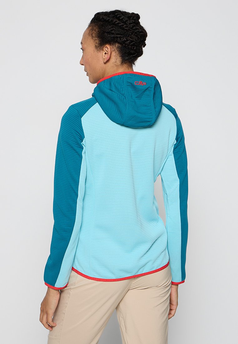 Veste en polaire légère bicolore en bleu clair et en sarcelle, dotée d'une capuche, d'une texture côtelée et d'un bord contrastant rouge le long de l'ourlet.