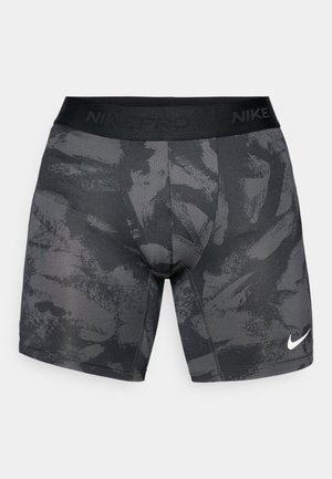 Shorts de sport noirs avec un motif texturé, taille élastique portant "NIKE PRO" et un petit logo Nike blanc sur le bas à l'avant.