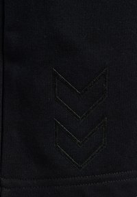 Zwarte stof met twee glanzende zwarte chevronstrepen die naar beneden wijzen, gestructureerd gebreid materiaal en een gestikte zoom aan de onderkant.