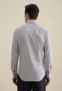 Witte langoe mouwen overhemd met een marineblauw ruitpatroon, button-down kraag en aangepaste pasvorm. Heeft een gebogen zoom en knoopmanchetten.