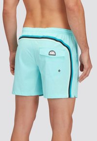 Costumi da bagno azzurro chiaro con una striscia laterale nera e blu, dotati di una tasca posteriore con alette e una piccola etichetta con logo.