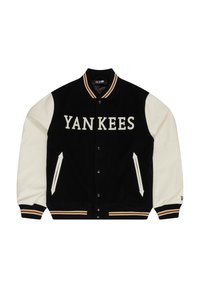 Svart og krem varsityjakke med "YANKEES" tekst. Den har ribbestrikket krage, trykknapper, sidelommer og kontrasterende stripede mansjetter.