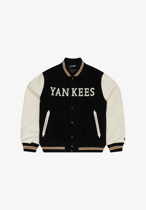 Jachetă de tip varsity neagră și crem cu textul "YANKEES". Prezintă guler ribbit, nasturi tip snap, buzunare laterale și manșete contrastante cu dungi.