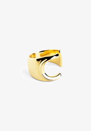 Anillo de metal en tono dorado con una banda ancha y un diseño curvado estilizado abierto en un lado. Superficie lisa y brillante con un acabado pulido.