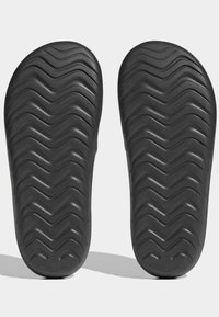 Semelles de sandales en caoutchouc noir avec un motif texturé ondulé pour une meilleure adhérence. Édges arrondis et finition lisse.