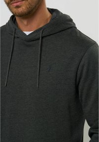 Hanorac cu glugă de culoare gri închis, fabricat dintr-un material moale, dotat cu o batista în față. Are șnururi și un mic emblema pe piept.