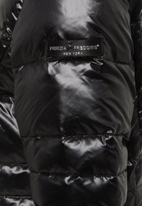 Czarna pikowana kurtka puchowa o błyszczącej, przeszywanej fakturze. Zawiera czarną metkę z białym napisem: „FRIEDA & FREDDIES NEW YORK.”
