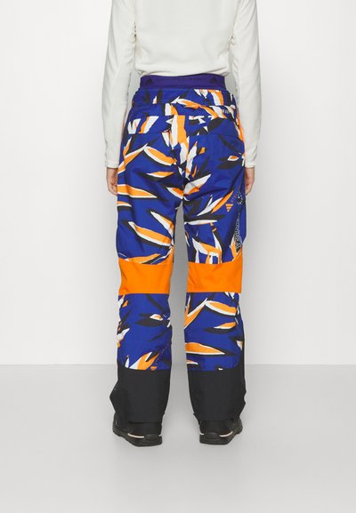 Multikleurige sneeuwbroeken met een blauw en oranje ontwerp en gedurfde patronen. De broeken hebben een elastische tailleband en zwarte boorden bij de enkels.