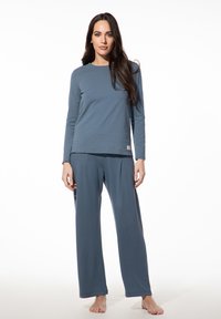 Blaues Langarmoberteil mit rundem Ausschnitt, kombiniert mit passenden weit geschnittenen Hosen. Weicher, glatter Stoff; minimalistisches Design; keine sichtbaren Muster oder Akzente.