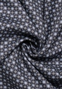 Tessuto nero con un motivo ripetuto di cerchi azzurri e forme a croce, creando un design testurizzato e intricato.