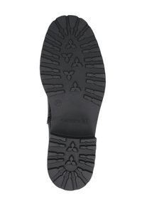 Suela de goma negra con diseño de textura en la banda de rodadura, con un patrón circular central y acentos triangulares. Tacón ligeramente elevado, marcado 'Caprice.'