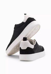 Svarta sneakers med texturerat läder och anteckningar i mocka. Har en vit gummisula och en broderad logotyp på hälen. Minimalistisk design.