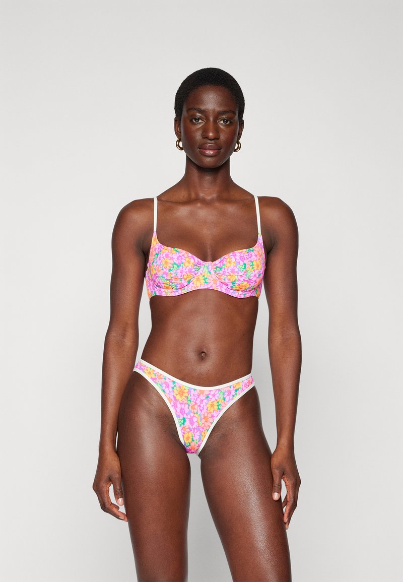 Bikini-Set mit Blumenmuster, bestehend aus einem gerafften Bustier-Oberteil mit dünnen Trägern und hochgeschnittenen String-Tangas. Farben sind Pink, Orange und Grün.