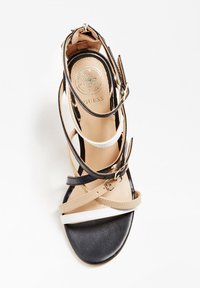 Korkokenkä, jossa on hihnat ja joka koostuu mustasta, beigestä ja valkoisesta synteettisestä materiaalista. Sisältää useita hihnoja ja kultasävyisen yksityiskohdan.