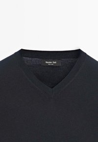 Pull noir à col en V en tissu tricoté. Présente un col côtelé et une texture subtile. L'étiquette indique "Massimo Dutti."