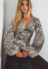 Leopard print blouse with long, voluminous sleeves, made from lightweight fabric featuring a neutral palette of beige and black.
