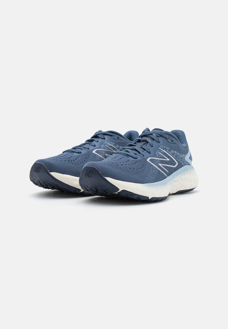 Zapatillas deportivas azules con parte superior de malla, acentos blancos, punta redonda, suela acolchada y suela de goma texturizada.