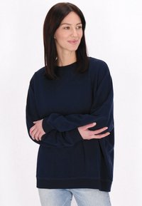 Námornícka modrá mikina s kulatým výst�řihem, dlouhými rukávy a volným střihem. Vyrobena z měkké, strukturované tkaniny s žebrovaným lemem.