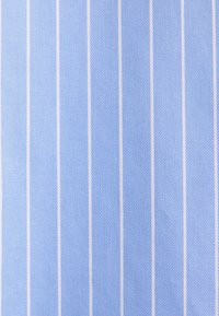 Hellblauer Stoff mit diagonalen Streifen und weißen Linien, der ein strukturiertes Muster zeigt. Das Design wirkt gleichmäßig und glatt.