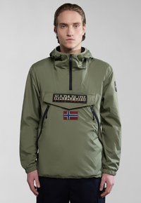 Chaqueta pullover de nailon verde con un bolsillo frontal, cremallera, parche con logo y detalle de bandera noruega. Puños elásticos y capucha para un ajuste ajustable.