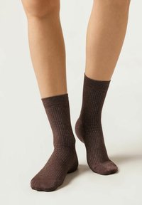 Calcetines marrones de canalé hechos de un material texturizado, con un sutil brillo metálico, que llegan a la mitad de la pantorrilla.