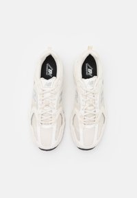 Bílé běžecké boty z mřížky se šedými doplňky, s polstrovanou podrážkou, šněrováním a logem na jazyku a boku.