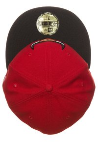 Gorra roja y negra con visera plana, hecha de tela. Presenta un logo en el frontal y detalles de costura. Etiqueta dorada en el interior.