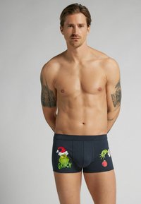 Boxer shorts de color azul oscuro con gráficos del Grinch, que incluyen un sombrero de Santa y adornos navideños, fabricados en un suave tejido elástico.
