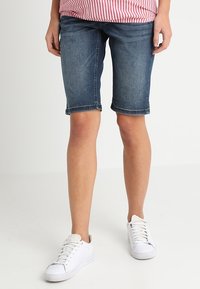 Denim bermudashorts i mörkblått, med medelhög midja och uppvikta fållar. Tillsammans med vita sneakers för en avslappnad och bekväm look.
