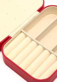 Boîte à bijoux rouge avec un intérieur en beige doux, contenant six compartiments cylindriques pour ranger des bagues, présentant une texture lisse et un design précis.