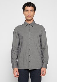 Grijs overhemd met lange mouwen en knopen, voorzien van een gestructureerde kraag, subtiele textuur en donkere knopen. Geen zichtbare patronen of accenten.