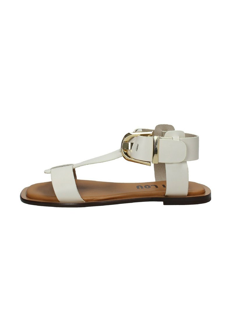 Sandali flat bianchi con design a T, dettagli in metallo dorato e suola marrone. Texture liscia con uno stile minimalista.