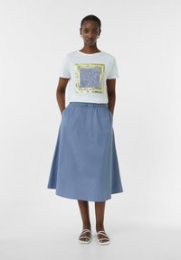 Lichtblauw crop t-shirt met een gestreepte vierkante grafiek, gecombineerd met een knielange blauwe rok met een elastische tailleband en zakken.