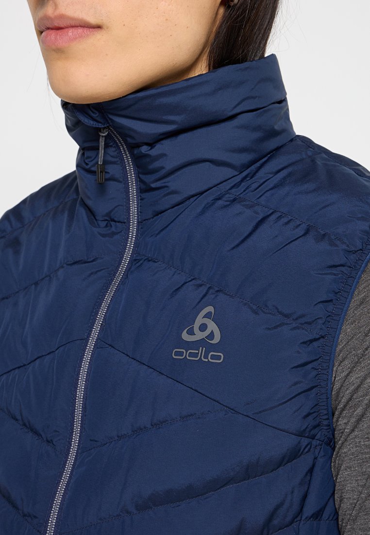 Marineblauer Steppwesten mit hohem Kragen, diagonalen Nähten, Reißverschluss und Logo-Akzent. Hergestellt aus einem glatten, synthetischen Material.