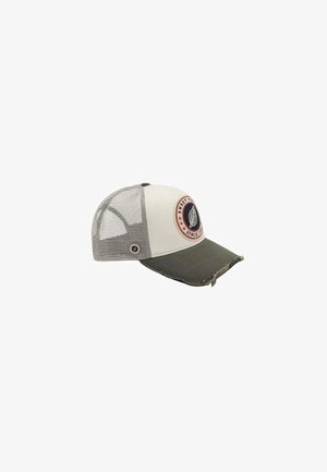 Casquette de camionneur beige et grise avec dos en maille, écusson rond avec une feuille et le texte "Sweet since 1983", et bord de visière usé.