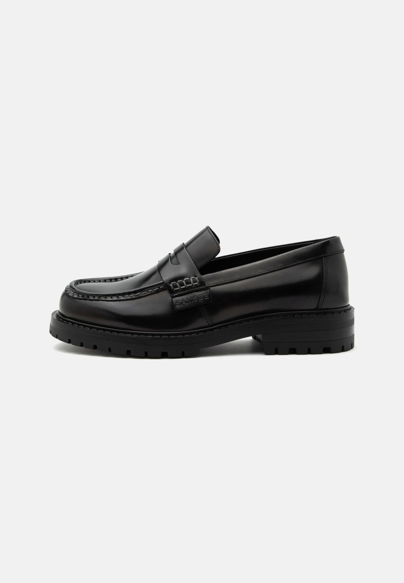 Mocassin en cuir noir poli avec semelle en caoutchouc épaisse et détail moc cousu, embossé sur le côté avec un nom de marque.