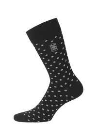 Chaussettes noires avec un poignet côtelé, présentant un motif à pois blancs et un petit logo près du poignet. Fabriquées en tissu doux.