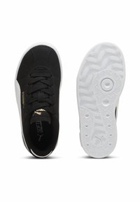 Ténis negros com um upper de tecido texturizado, colarinho almofadado e sola de borracha branca com um padrão ondulado. Acentos de logo dourado na lateral.