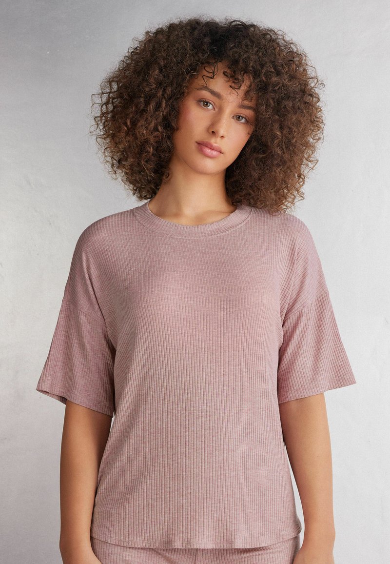 Ruffsad rosa t-shirt med korta ärmar och rund halsringning, tillverkad av mjukt tyg. Har en avslappnad passform och subtil textur.