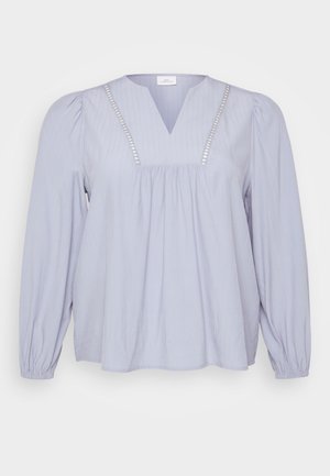 Light blue blouse made of soft fabric, featuring a V-neck, vertical ribbing, and decorative accents along the neckline. Long, gathered sleeves.