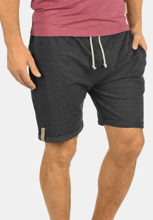 Shorts gris foncé en tissu doux, dotés d'une taille élastique avec cordon de serrage. Comprend des ourlets roulés et une petite étiquette de marque sur le côté.