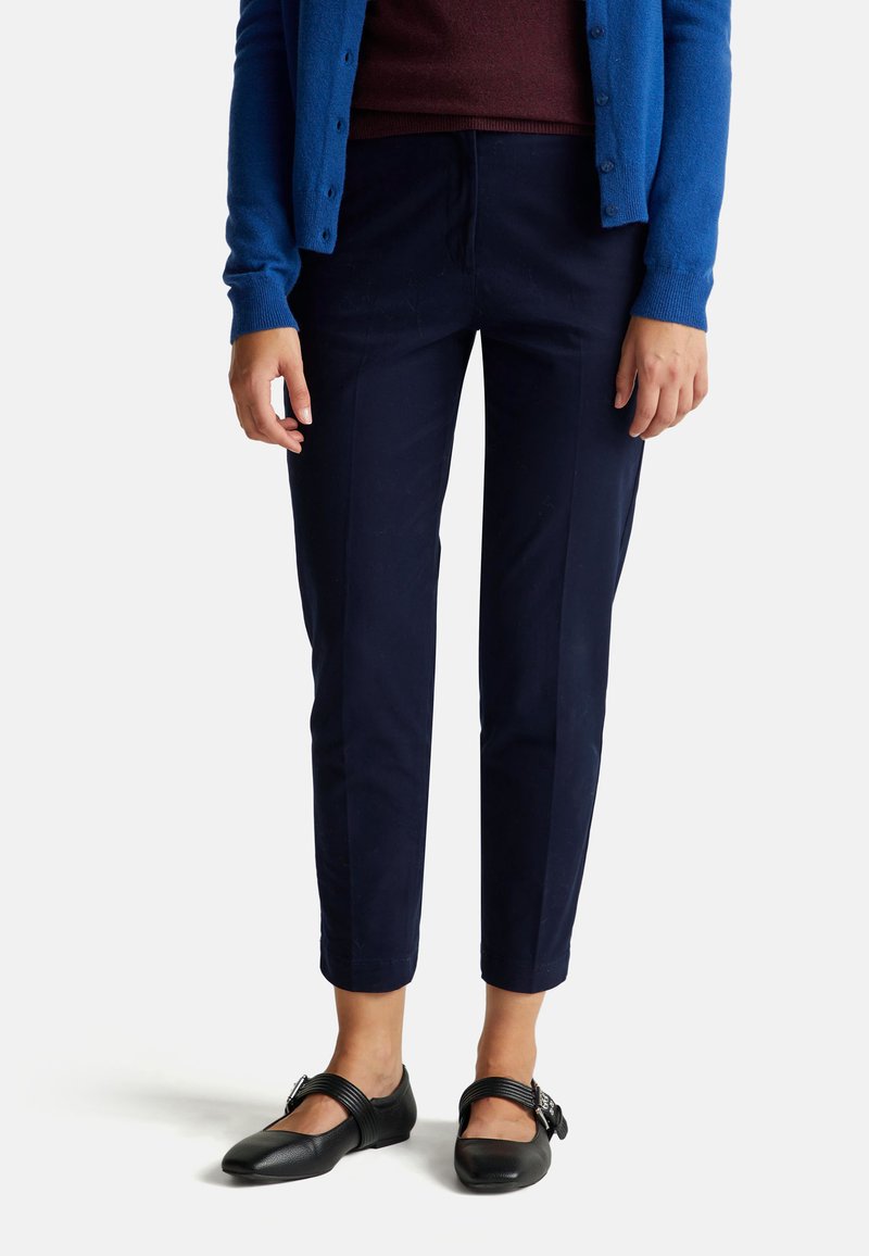 Granatowe spodnie o dopasowanym kroju, wykonane z gładkiego materiału, z prostym krojem i długością do kostek, w połączeniu z czarnymi płaskimi butami.