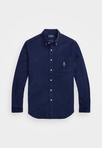 Mörkblå kordflöjelskjorta med långa ärmar, knappad krage, vita knappar och bröstficka med en liten broderad björn.