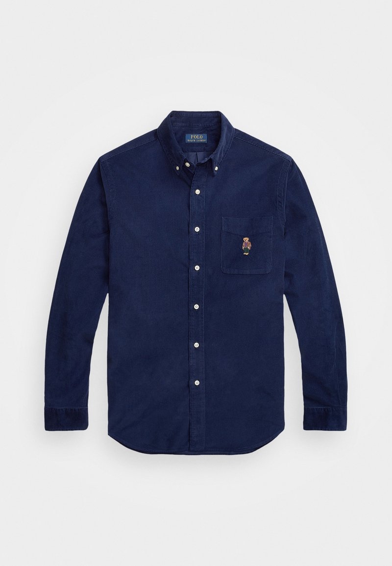 Mörkblå kordflöjelskjorta med långa ärmar, knappad krage, vita knappar och bröstficka med en liten broderad björn.