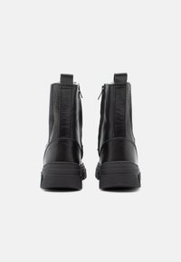 Sorte svarte skinnboots til ankelen med en jevn tekstur, doble glidelåser på sidene og en kraftig gummisåle for bedre grep og holdbarhet.