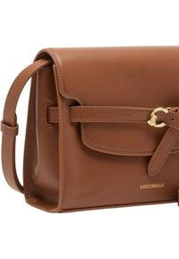 Hnědá kožená kabelka s pevnou konstrukcí, vybavená předním klopovým uzávěrem, prošitými detaily a ozdobou z kovu se zlatým tónem.