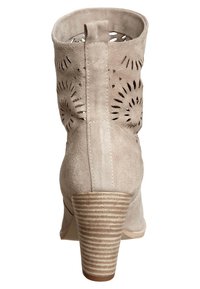 Beżowy zamszowy botek za kostkę z wycięciami, obcasem na słupku i gładką fakturą. Charakteryzuje się paskowanym obcasem i zaokrąglonym noskiem.